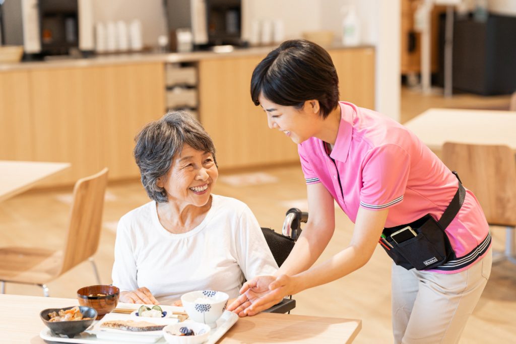高齢女性の食事を出す介護職員のイメージ画像